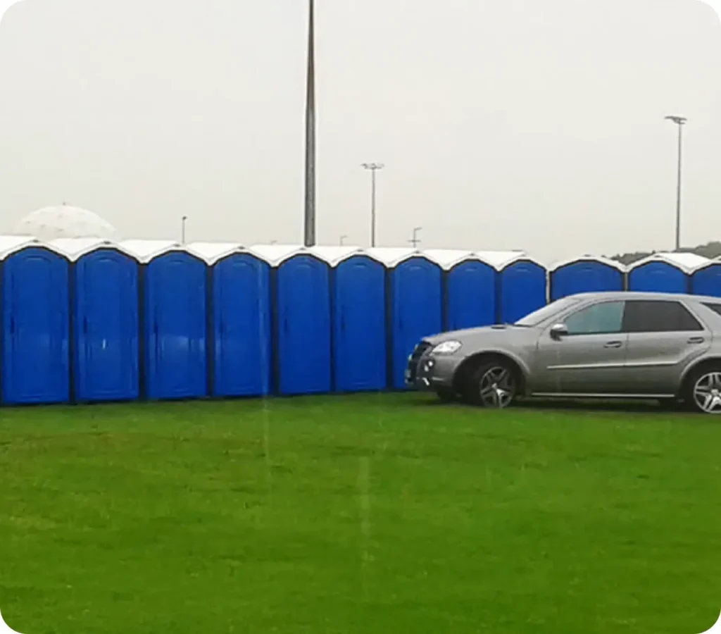 Reihe blauer Toilettenkabinen auf einer Wiese